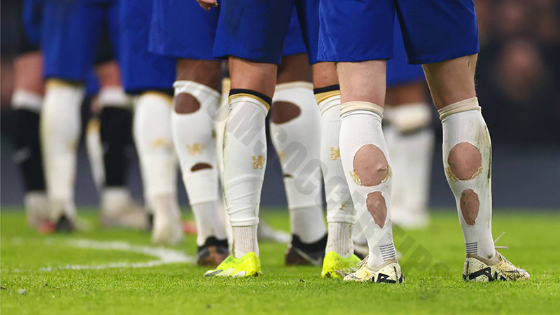 Why do football players cut holes in their socks?